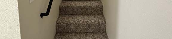 A long hallway with a carpeted floor and a wall of patterned curtains.